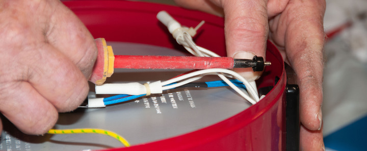 A close up image of fingers holding a wiring tool and electrical wires A close up image of fingers holding a wiring tool and electrical wires