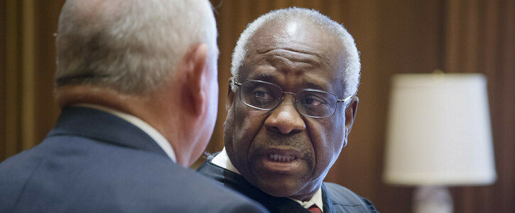 Photo: US Department of Agriculture. Description: Justice Clarence Thomas speaks with a man in a wood-paneled room.