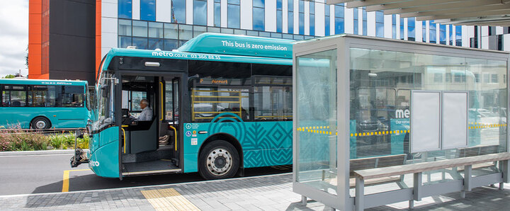 A metro bus is parked outside a bus stop.