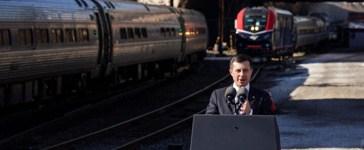 Secretary of Transportation Pete Buttigieg standing in front of Amtrak train