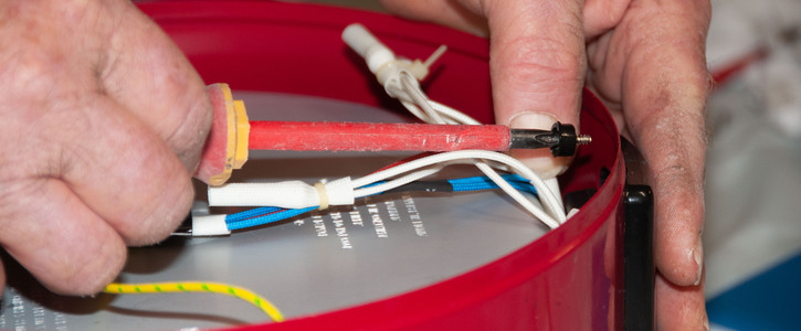 A close up image of fingers holding a wiring tool and electrical wires 